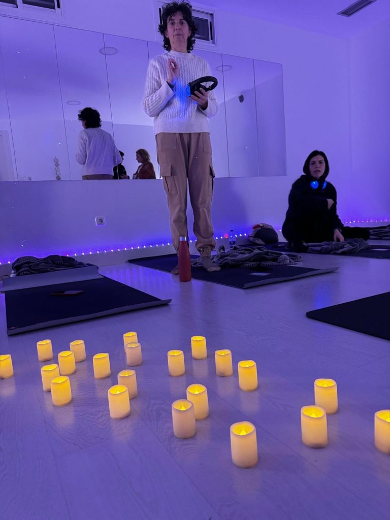 Taller de Breathwork con auriculares en Eibar con Lorena Carnevali, grupo meditando en sala iluminada con velas y luces tenues