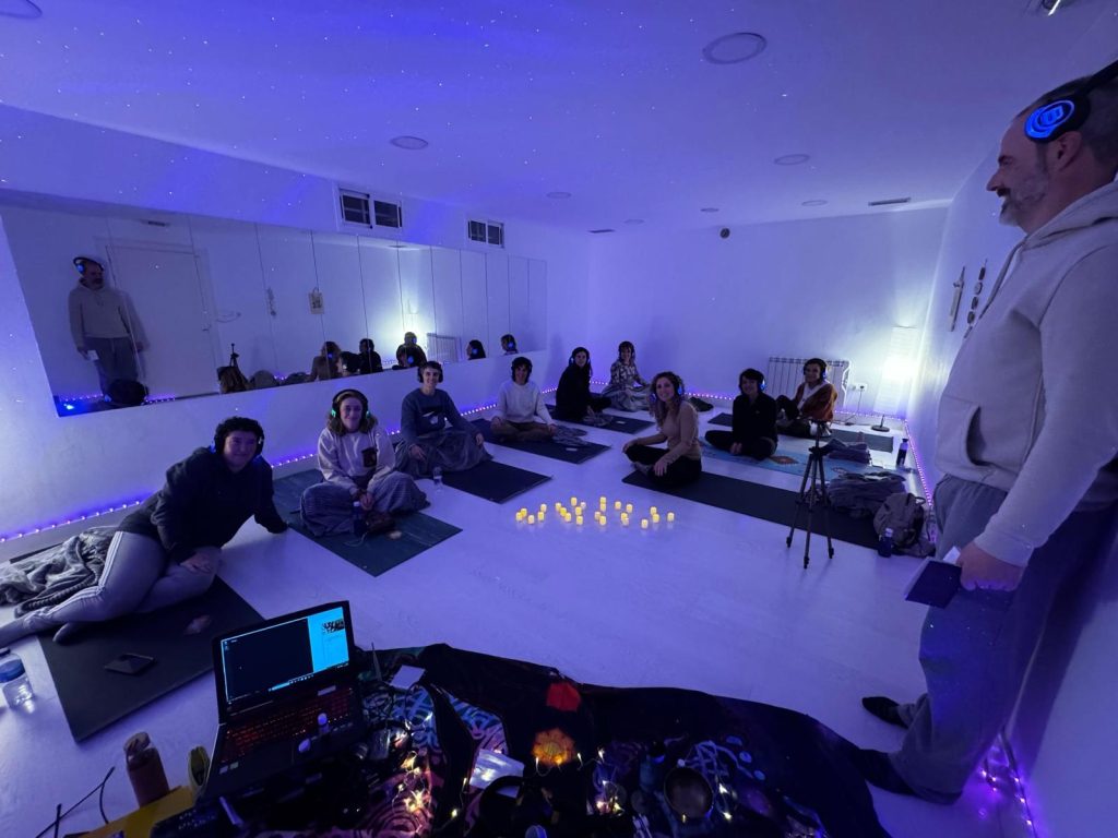 Taller de Breathwork con auriculares en Eibar con Lorena Carnevali, grupo meditando en sala iluminada con velas y luces tenues