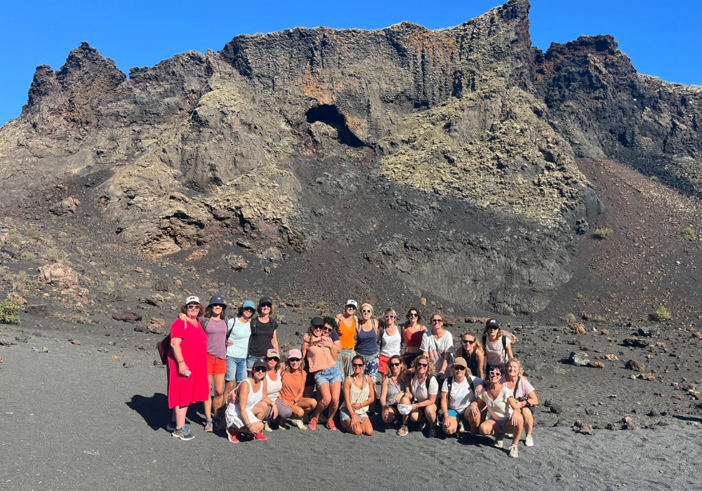 Grupo de mujeres en entorno volcánico durante una ruta de conexión con la naturaleza dentro de la experiencia Canarias de Lorena Carnevali Yoga & Bienestar.