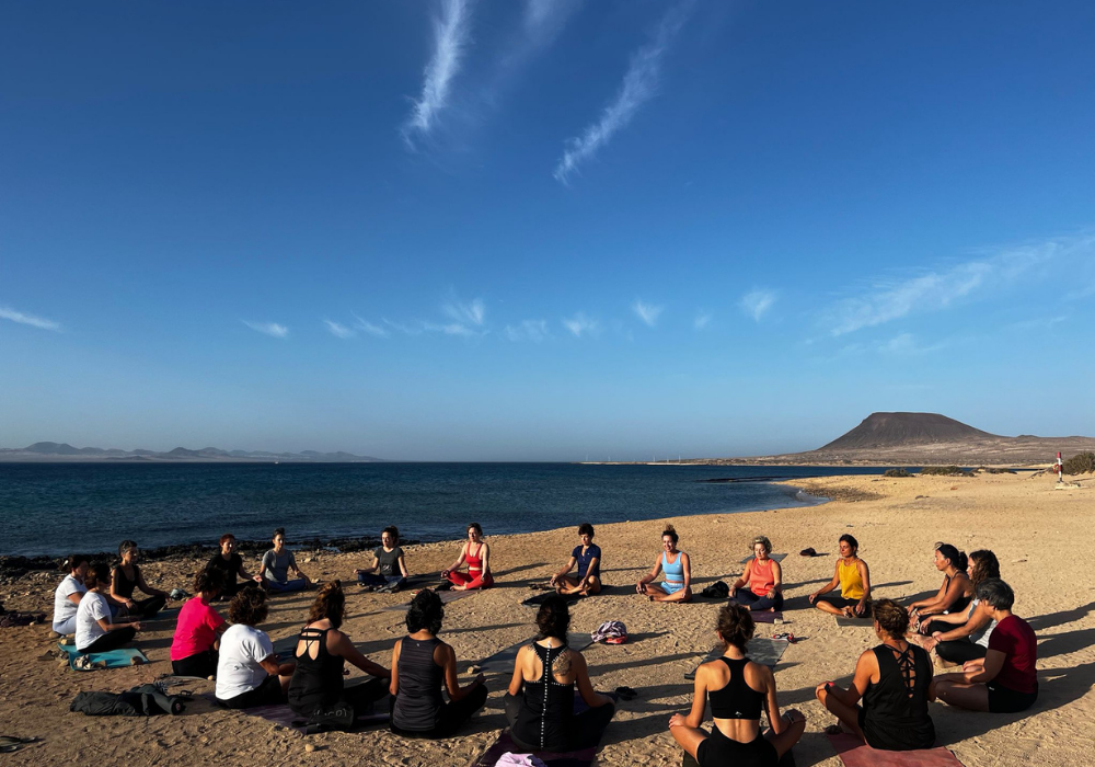 Dinámica de grupo en la arena frente al mar durante la Experiencia Canarias, con momentos de conexión, escucha y reflexión.